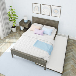 Modern gray wooden bed with pull-out trundle mattress, white quilted bedding and pastel blue and pink pillows in a bright bedroom with matching nightstand, potted plant, framed wall art and herringbone hardwood floor
