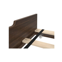 Wooden bed frame corner with dark stained headboard and reinforced slats.