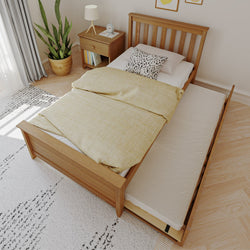 Single wooden trundle bed with pull-out mattress, yellow duvet and spotted accent pillow in bright modern bedroom with nightstand, lamp and potted plant