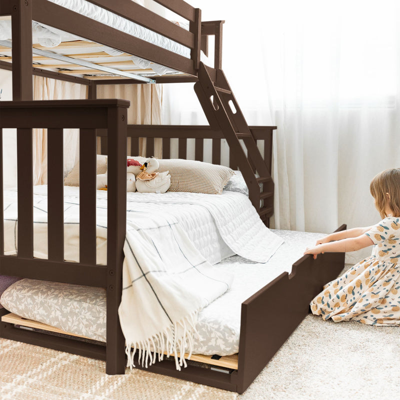 Brown wooden twin-over-full bunk bed with ladder and pull-out trundle, white quilted bedding, gingham pillows and plush toys in a bright kids' bedroom