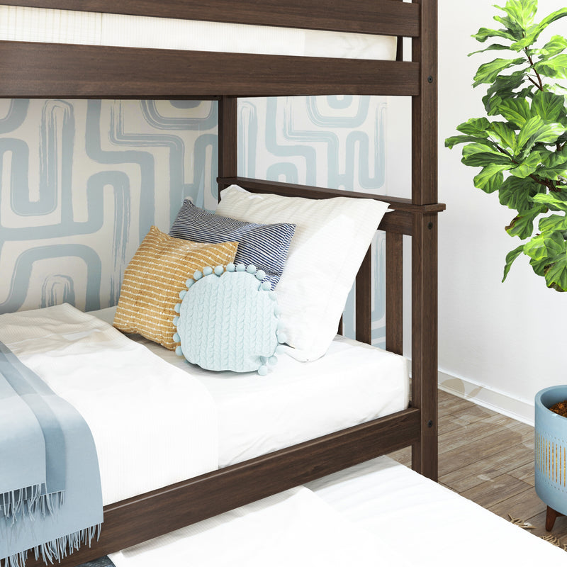 Modern dark wood bunk bed close-up with white bedding, striped and textured decorative pillows, blue geometric wallpaper and a fiddle-leaf fig plant in a styled kids' bedroom