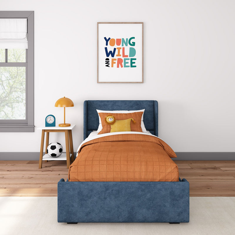 Children's bedroom with framed "Young Wild and Free" poster, navy upholstered bed, orange bedding, bedside lamp, clock and soccer ball