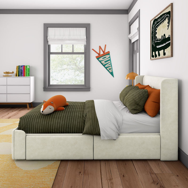 Bright modern kids' bedroom with green striped bedding, fox plush, orange pillows, white dresser with books, gray-trimmed window, "Oliver" pennant and framed dinosaur wall art over hardwood floor