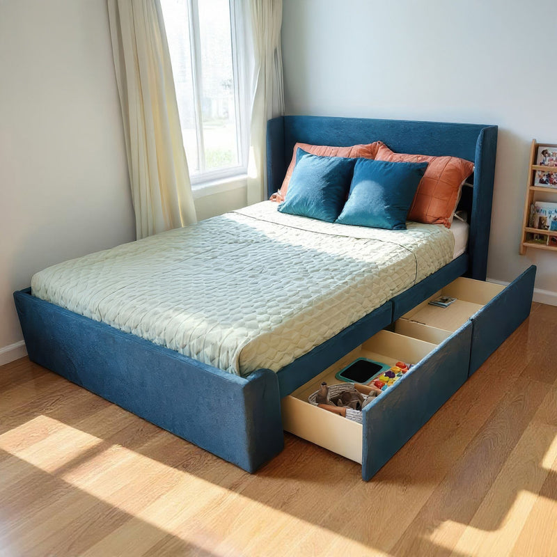 Blue upholstered storage bed with pull-out drawers, teal and orange pillows in sunlit modern bedroom