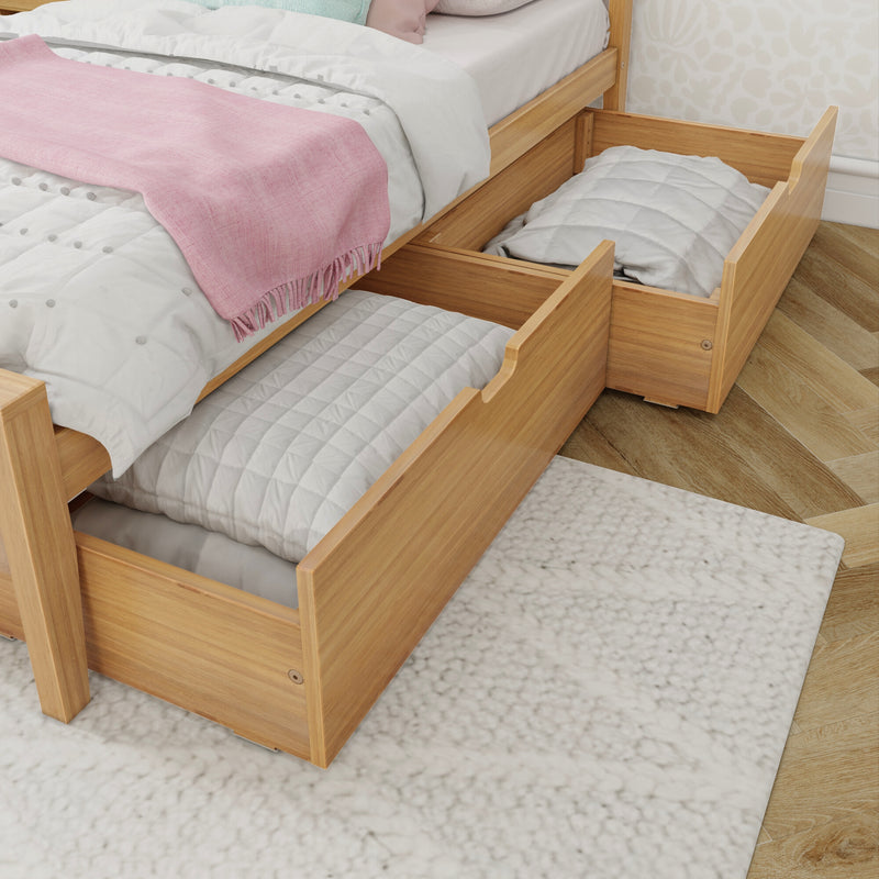 Under-bed storage drawers in a wooden bed frame holding quilts and pillows with a pink throw on white bedding — space-saving bedroom storage solution