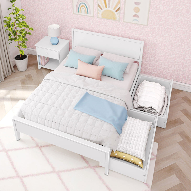 White wooden storage bed with two under-bed drawers, pastel quilted bedding and decorative pillows in a pink patterned bedroom with nightstand and plant