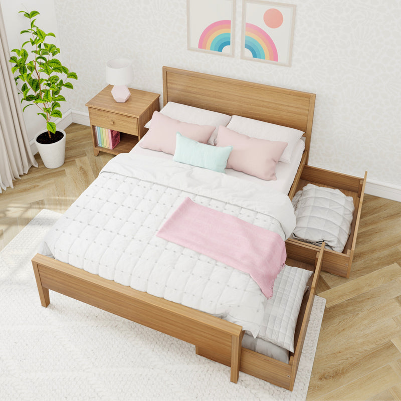 Modern minimalist bedroom with wooden platform bed and under-bed storage drawer, white quilted bedding, pastel pink throw and pillows, wooden nightstand with geometric lamp, potted plant and rainbow wall art on light herringbone hardwood floor