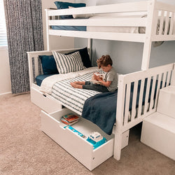 Child reading on white bunk bed with pull-out storage drawers in cozy children's bedroom.