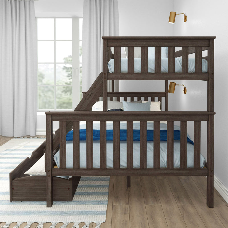 Dark wood twin-over-full bunk bed with side stairs and under-bed storage drawer, blue bedding and pillows, brass wall sconces, large window with light gray curtains on hardwood floor