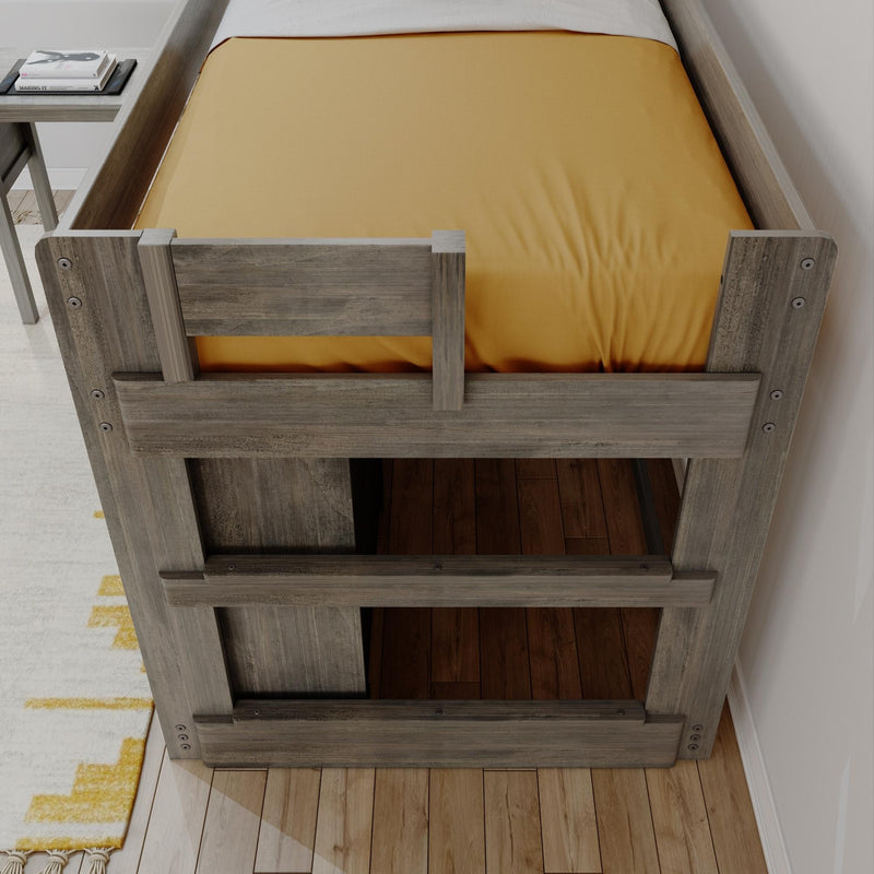 Top-down view of a rustic gray wood twin loft bed with mustard fitted sheet, visible under-bed storage opening, hardwood floor and bedside table with books in a modern farmhouse bedroom