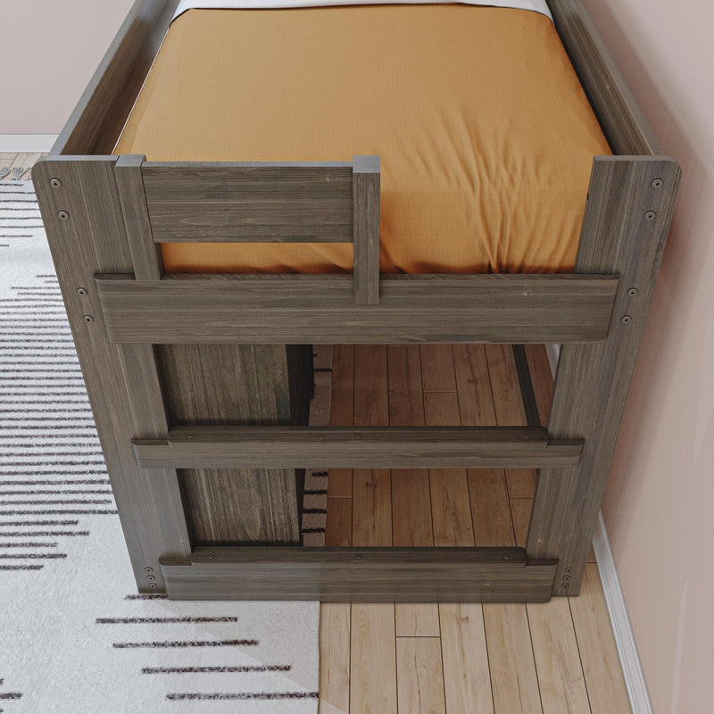 Gray wood twin bunk bed end with safety rails and orange fitted sheet in a kids' bedroom on hardwood floor with striped rug