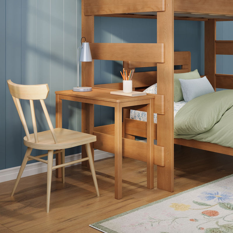 Wooden bunk bed with built-in study desk, lamp and chair in kids' bedroom — blue paneled wall, green bedding and floral rug