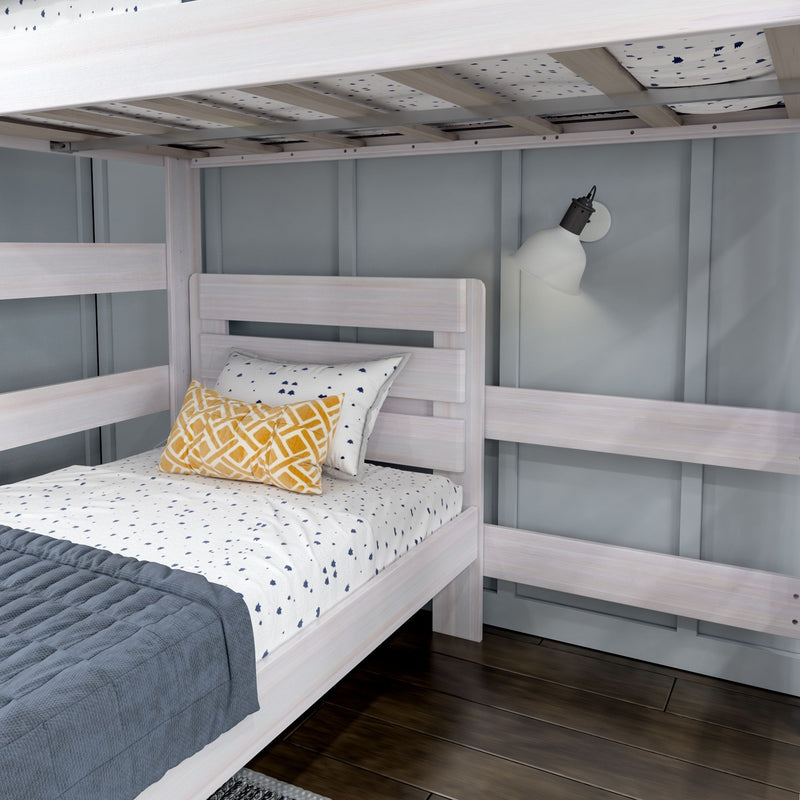 Whitewashed wooden bunk bed in modern kids' bedroom with gray paneled wall, blue quilt, patterned yellow pillow, wall-mounted reading lamp and dark hardwood floor