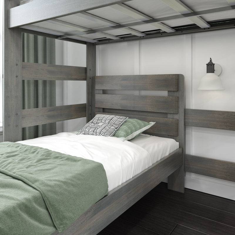 Gray wooden twin bunk bed with green blanket and patterned pillow on white sheets against paneled wall with black wall sconce