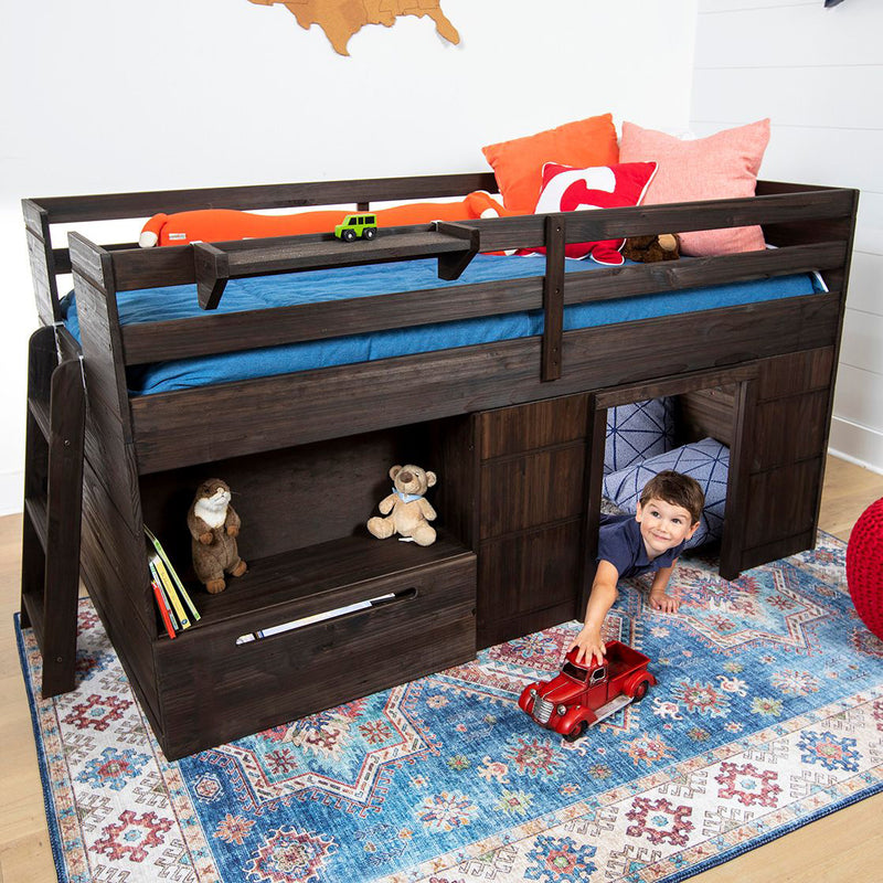 Dark wood kids loft bed with built-in storage cubbies and playhouse, blue bedding and pillows, child reaching for red toy truck on patterned rug