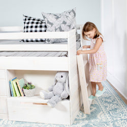 Child climbing ladder into white wooden kids loft bed with built-in storage, plush gray bunny, children's books and patterned pillows in a pastel bedroom