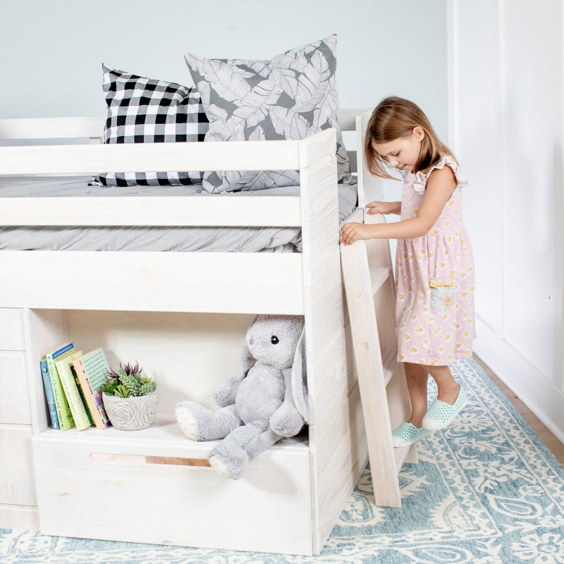 White wooden loft bunk bed with patterned pillows, stuffed bunny, children's books and a young girl climbing the ladder on a blue rug