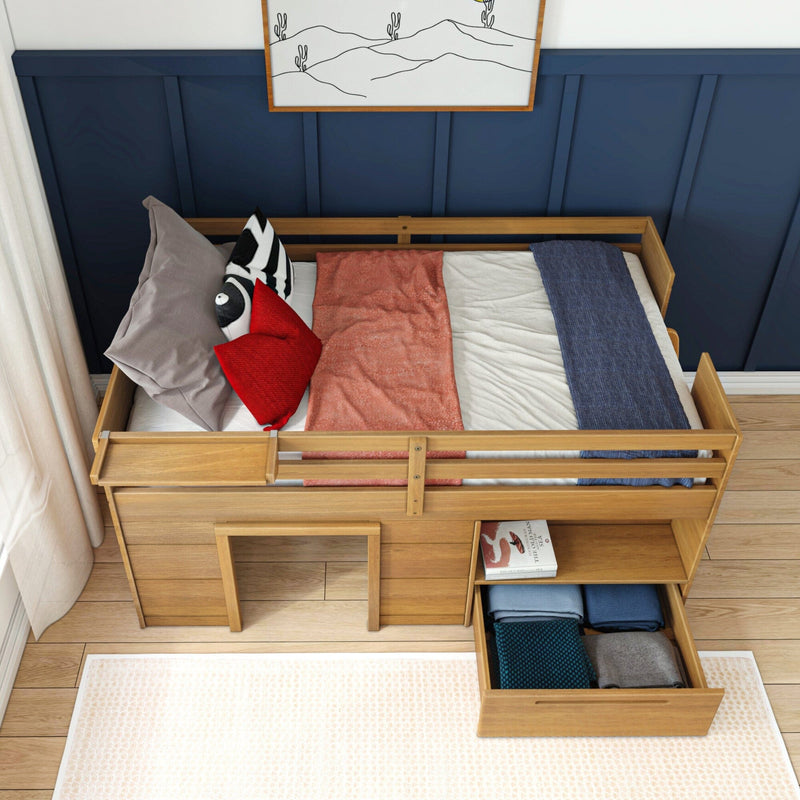 Modern wooden kids loft bed with safety rails and built-in storage drawer and shelves, navy accent wall, red and gray pillows and blue throw on mattress