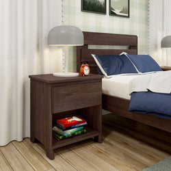 Modern bedroom with wooden nightstand featuring a lamp and alarm clock, next to a bed with blue pillows and books stored below, showcasing stylish and functional bedroom furniture.