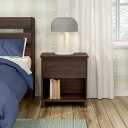 Wooden nightstand with books and a modern gray lamp beside a bed with blue bedding.