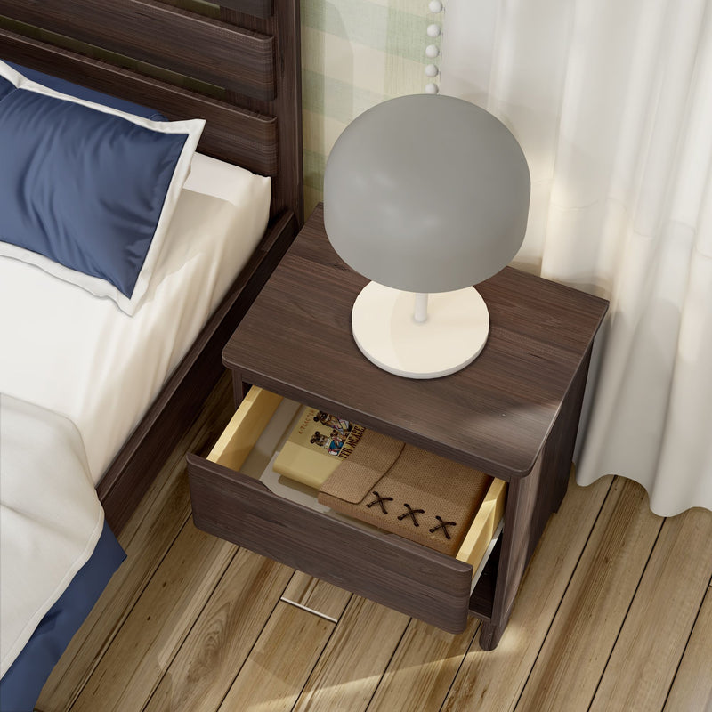Modern dark wood bedside table with round white lamp and open drawer beside a bed with navy pillow, hardwood floor and white curtains