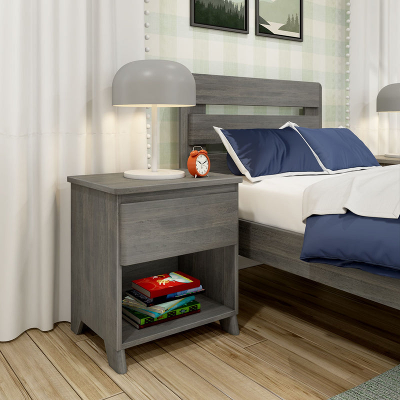 Modern bedroom nightstand with gray lamp and orange alarm clock, navy blue pillows on gray wood headboard, books on lower shelf