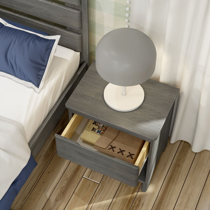 Gray wooden nightstand with round modern bedside table lamp and open drawer containing notebook and book beside bed with navy blue pillow on hardwood floor, bedroom decor