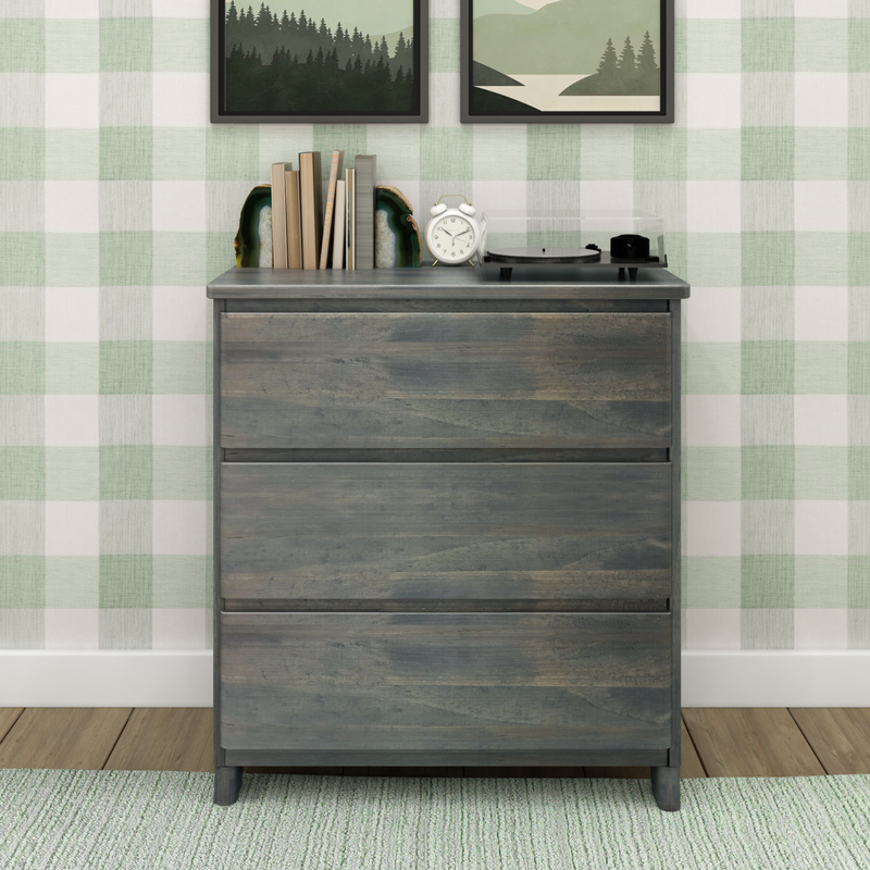 Rustic gray wooden dresser with record player, books, agate bookends and white alarm clock against green buffalo check wallpaper and framed landscape prints