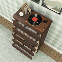 Turntable on wooden dresser with open drawers filled with neatly folded blankets and books nearby.