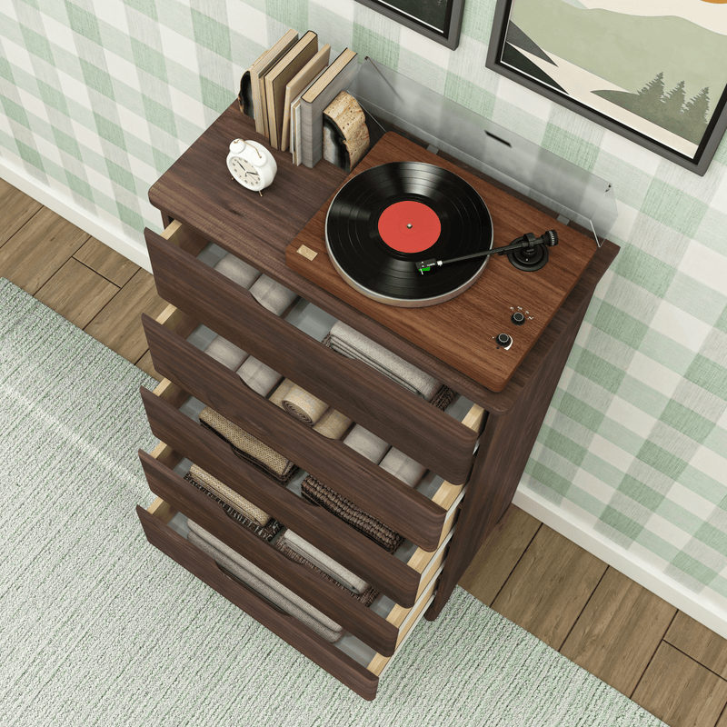 Turntable on wooden dresser with open drawers filled with neatly folded blankets and books nearby.