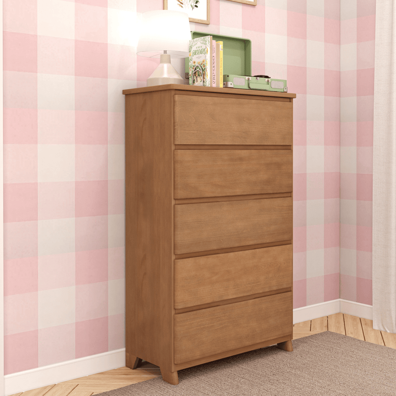 Wooden five-drawer dresser in a cozy bedroom with pink checkered wallpaper.