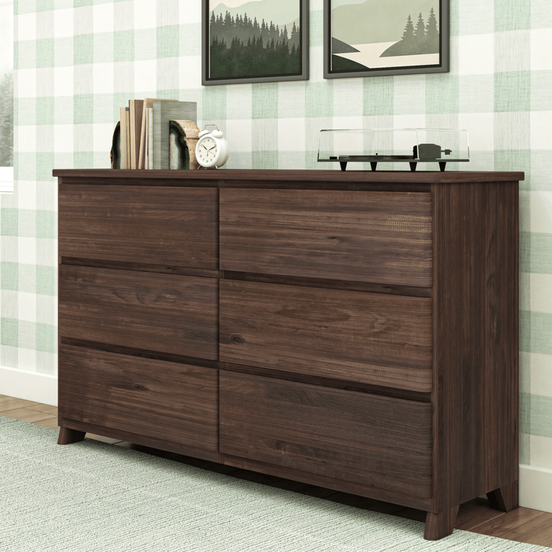 Wooden six-drawer dresser in modern bedroom with plaid wallpaper and decorative plants on top.