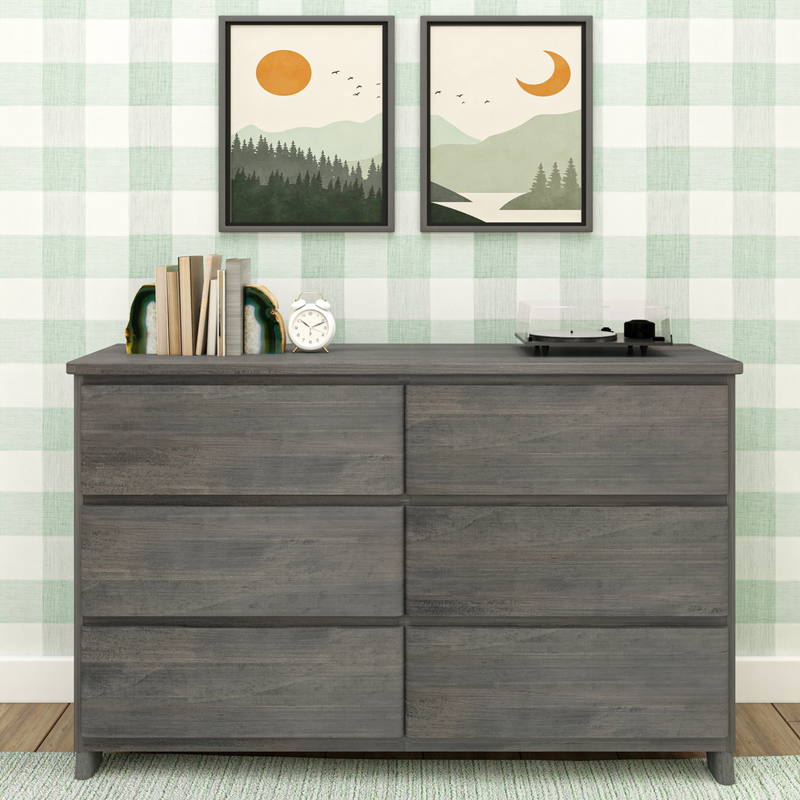 Modern rustic grey wooden dresser against green plaid wallpaper with twin framed minimalist mountain prints, geode bookends, books, white alarm clock and vinyl record player