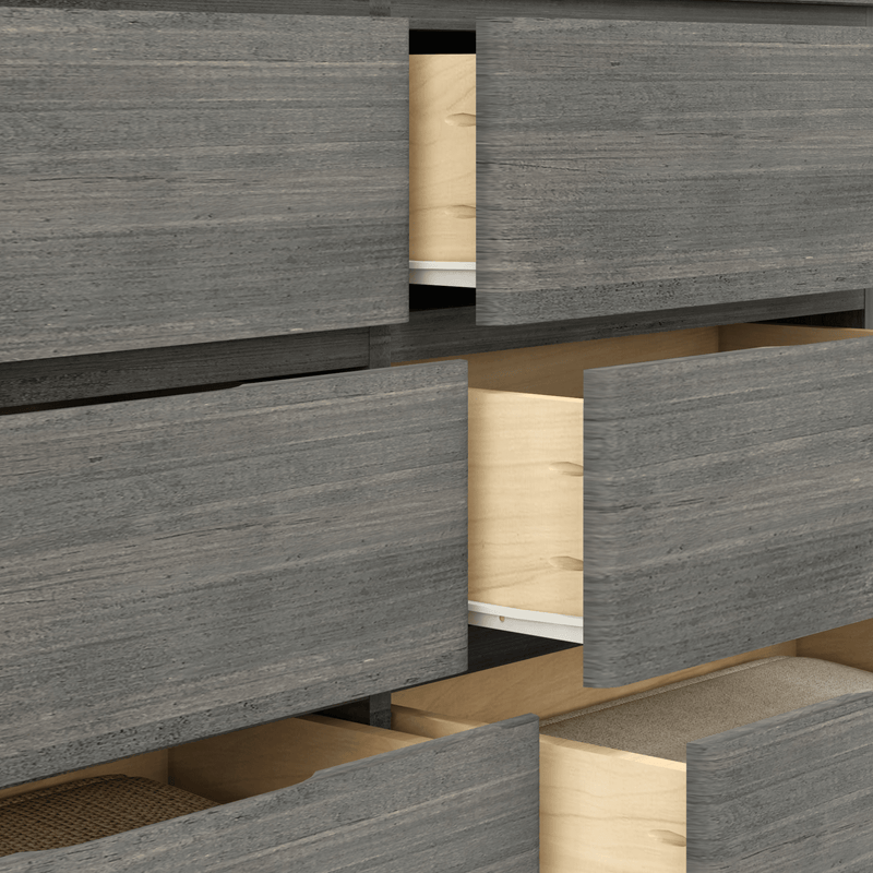 Close-up of modern gray wood dresser with multiple partially open drawers revealing light natural wood interiors and folded linens, ideal bedroom storage and organization