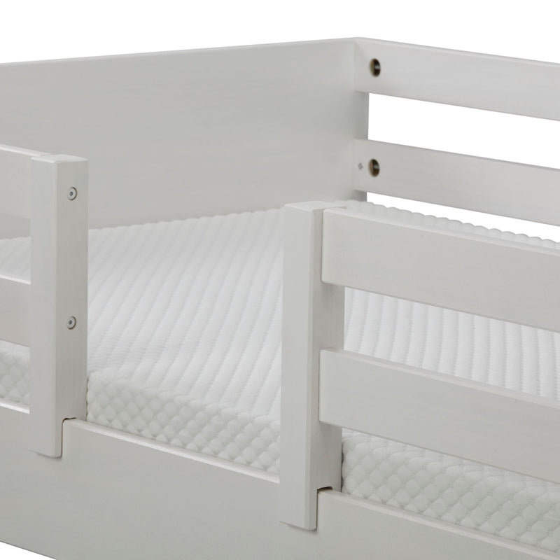 Close-up of white wooden bed guard rail and textured mattress cover on a modern bunk bed frame, nursery safety rail detail