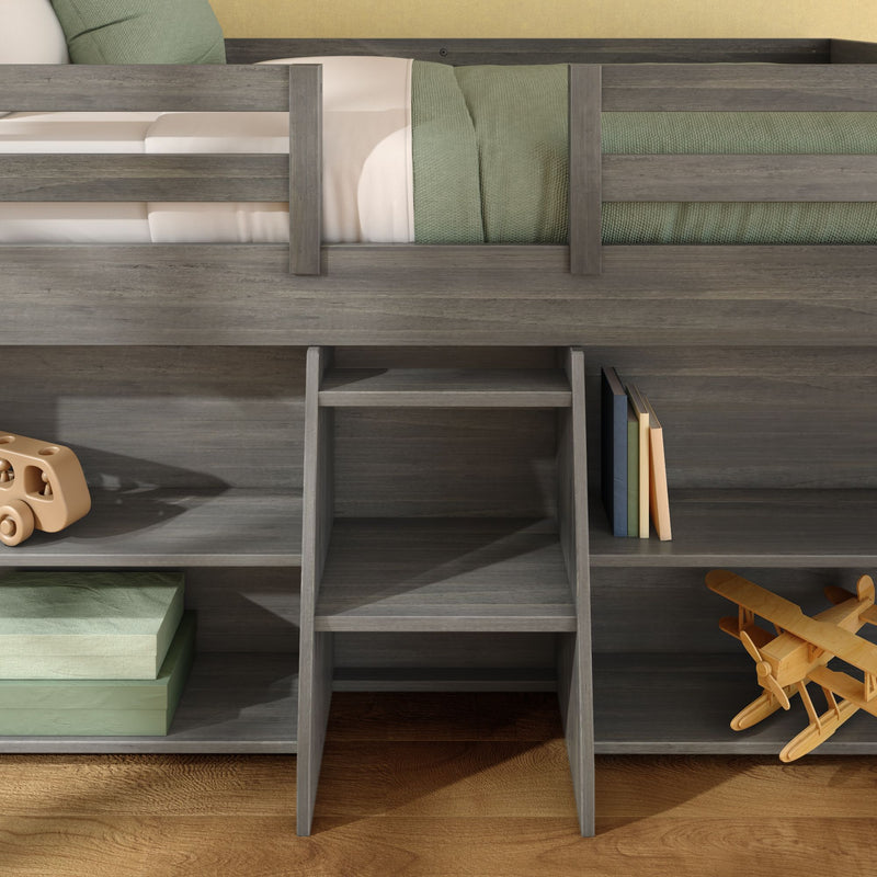 Gray wood loft bed with built-in ladder and cubby storage, green bedding, stacked books and wooden toy airplane in children's bedroom