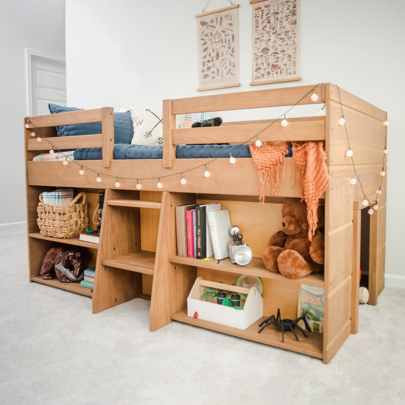 Wooden kids loft bed with built-in storage shelves, cozy blue bedding, string lights, books, toys and wicker basket