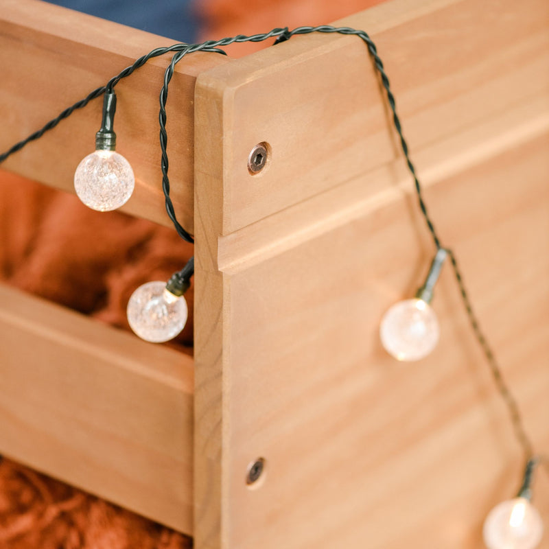 Globe string lights draped over natural wood frame creating warm outdoor patio lighting for deck, pergola, or backyard ambiance