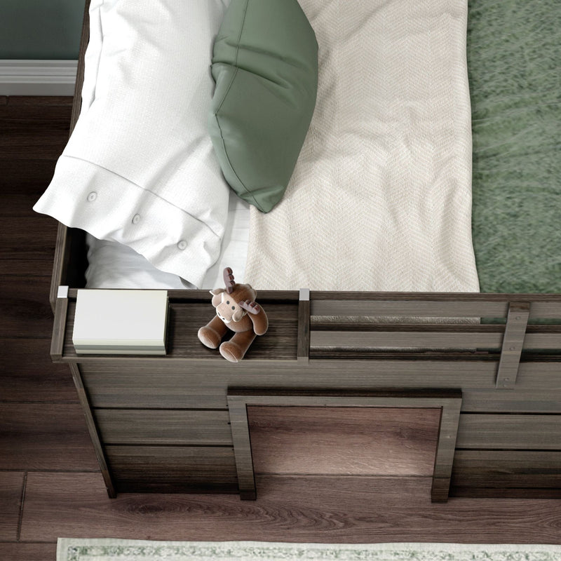 Top-down view of rustic wooden toddler bed with white buttoned pillow, green throw cushion, beige blanket, book and plush moose toy — children's bedroom nursery decor