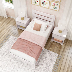 Single bed in cozy bedroom with pink bedding, white nightstands, and floral wall art.