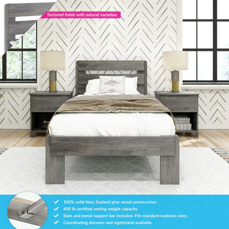 Grey solid wood bed frame with slatted headboard, matching nightstands and lamps in farmhouse bedroom with chevron wallpaper