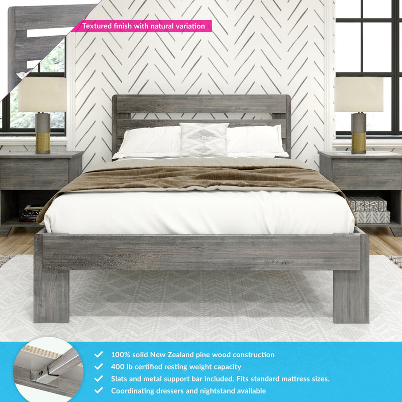 Rustic gray solid pine wood bed frame with slatted headboard, white bedding and decorative pillow, flanked by matching nightstands and lamps against chevron-patterned wallpaper — textured finish with natural variation, modern farmhouse bedroom decor