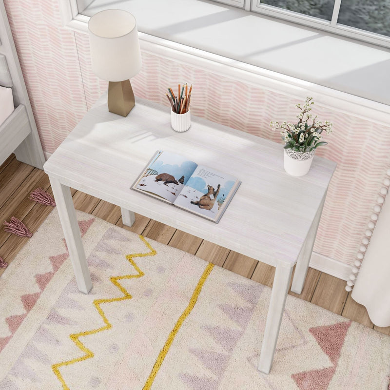Small white desk with open book, lamp, pencils, and potted plant in a cozy bedroom setting.