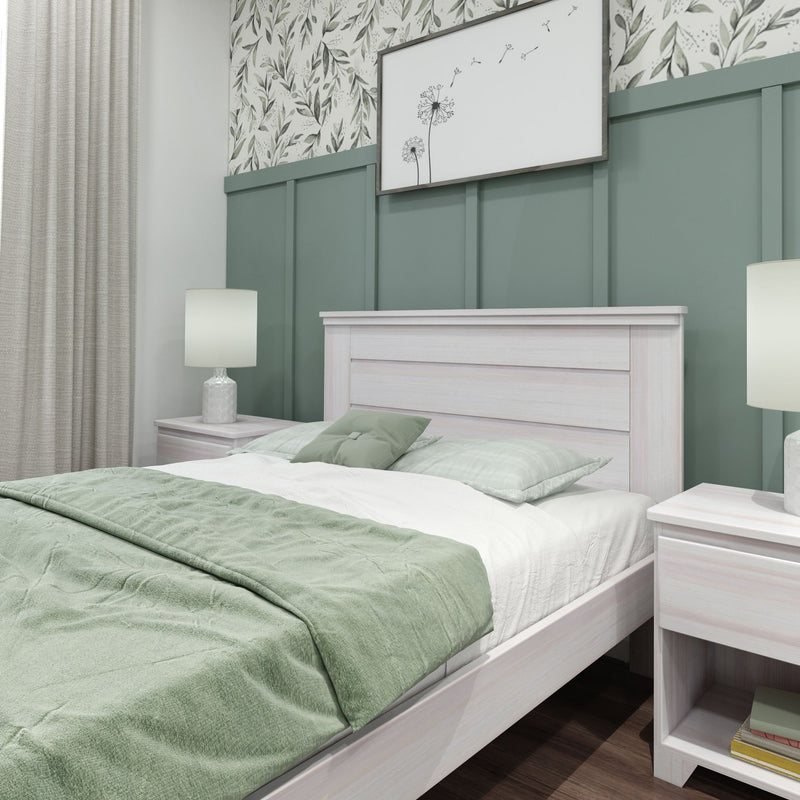 Cozy modern bedroom with sage green paneled accent wall, whitewashed wood bedframe, green bedding, bedside lamps and botanical wall art