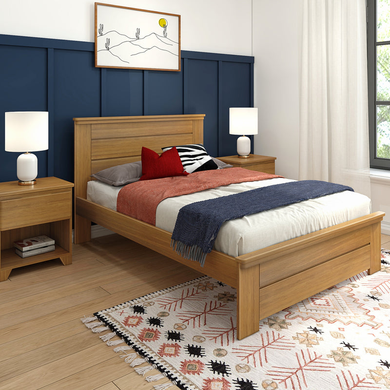 Modern bedroom with navy blue paneled accent wall, oak wood bed and nightstands, white table lamps, red and black accent pillows, rust textured throw and navy blanket, boho patterned rug and sheer linen curtains