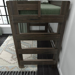 Wooden bunk bed ladder with green bedding and decorative rug in modern bedroom setting.
