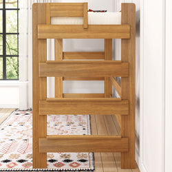 Wooden bunk bed with a white mattress in a bright, cozy bedroom setting.