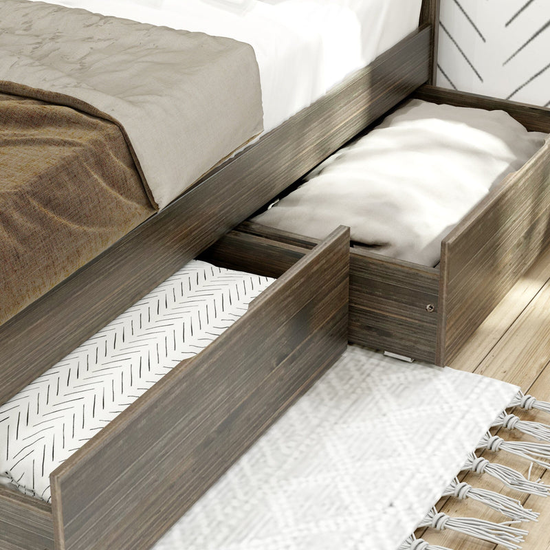 Rustic gray wood platform bed with under-bed storage drawers pulled out storing folded blankets and linens on light hardwood floor with patterned rug