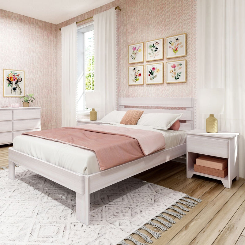Cozy pink bedroom with whitewashed wooden bed, blush duvet and pillows, floral gallery wall, sheer pom-pom curtains, gold bedside lamps and feminine decor