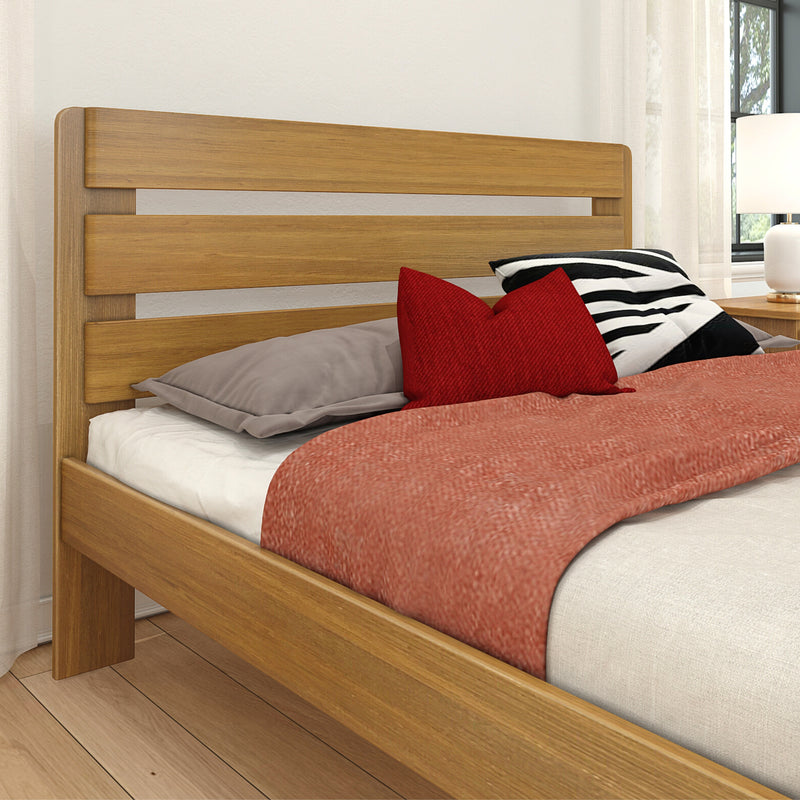 Oak slat headboard and platform bed with red accent pillows, black-and-white striped cushion, white bedside lamp and hardwood floor